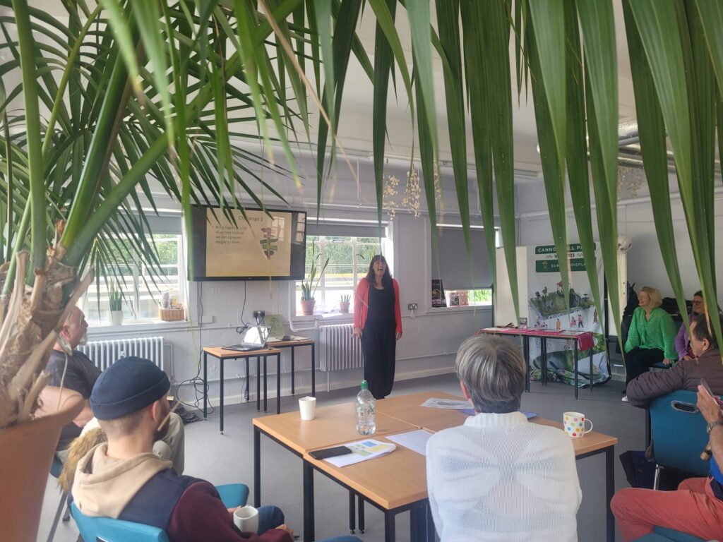 Dee giving a tree trails presentation - photographed through tree leaves