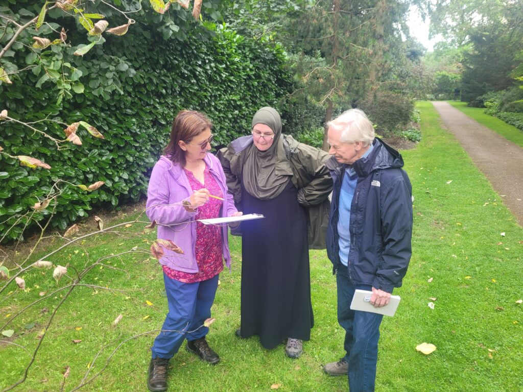 Nina showing Sonja and Martin, two new urban forest volunteers, how to survey a newly planted street tree during a practice session at Winterbourne Gardens.